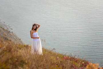 Image showing A beautiful tall slender girl stands on a hill by the sea