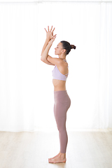 Image showing Portrait of gorgeous active sporty young woman practicing yoga in studio. Beautiful girl practice Garurasana, eagle yoga pose. Healthy active lifestyle, working out indoors in gym