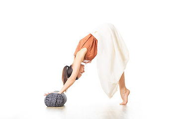 Image showing Restorative yoga with a bolster. Young sporty attractive woman in bright white yoga studio, stretching and relaxing during restorative yoga with bolster cushion. Healthy active lifestyle