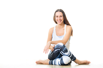 Image showing Young sporty female yoga instructor in bright white yoga studio, smiling cheerfully, looking at the camera.