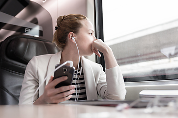 Image showing Businesswoman communicating on mobile phone while traveling by train.