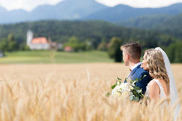 Image showing Bride hugs groom tenderly in wheat field somewhere in Slovenian countryside.