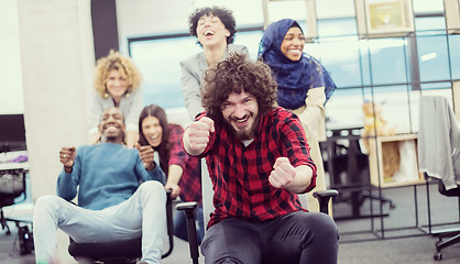 Image showing multiethnics business team racing on office chairs