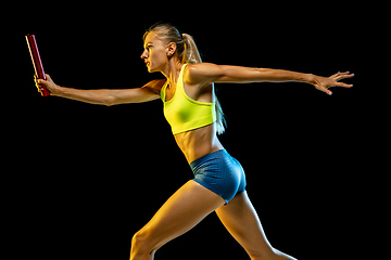 Image showing Professional female relay racer training on black studio background in neon light