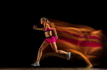 Image showing Professional female relay racer training on black studio background in mixed light