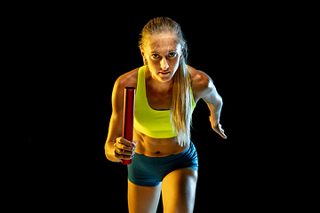 Image showing Professional female relay racer training on black studio background in neon light