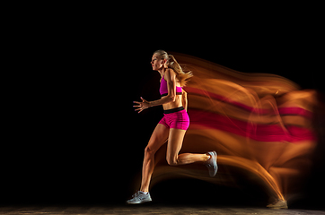 Image showing Professional female relay racer training on black studio background in mixed light