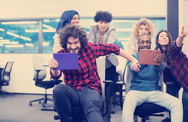 Image showing multiethnics business team racing on office chairs