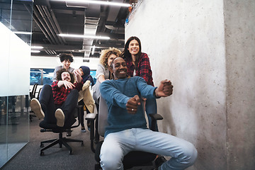 Image showing multiethnics business team racing on office chairs