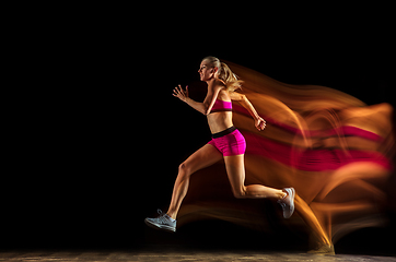 Image showing Professional female relay racer training on black studio background in mixed light