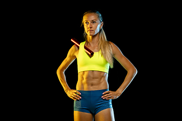 Image showing Professional female relay racer training on black studio background in neon light