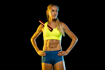 Image showing Professional female relay racer training on black studio background in neon light