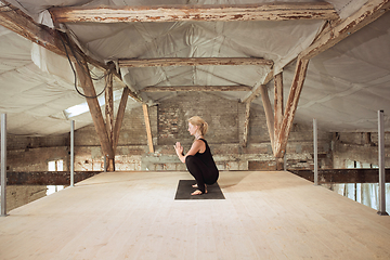 Image showing Young woman exercises yoga on an abandoned construction site