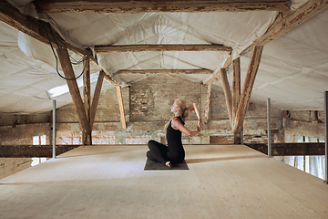 Image showing Young woman exercises yoga on an abandoned construction site