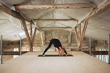Image showing Young woman exercises yoga on an abandoned construction site