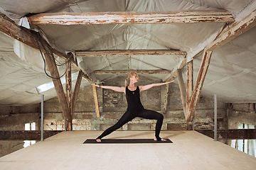 Image showing Young woman exercises yoga on an abandoned construction site