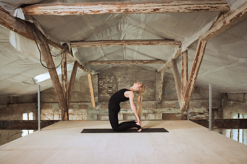 Image showing Young woman exercises yoga on an abandoned construction site