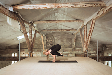 Image showing Young woman exercises yoga on an abandoned construction site