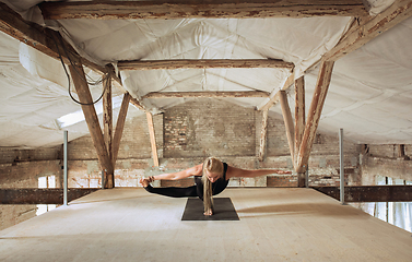 Image showing Young woman exercises yoga on an abandoned construction site