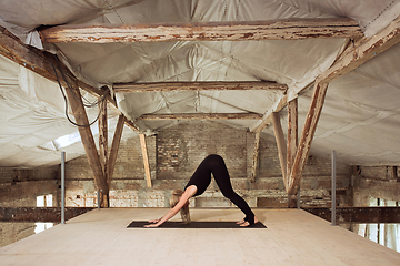 Image showing Young woman exercises yoga on an abandoned construction site