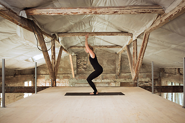 Image showing Young woman exercises yoga on an abandoned construction site