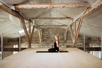 Image showing Young woman exercises yoga on an abandoned construction site