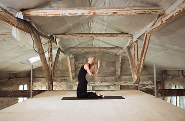 Image showing Young woman exercises yoga on an abandoned construction site