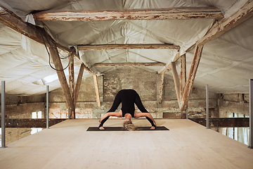 Image showing Young woman exercises yoga on an abandoned construction site