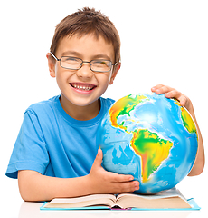 Image showing Little boy is examining globe