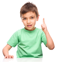 Image showing Little boy is pointing up using his index finger