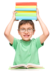 Image showing Little boy is holding a pile of books