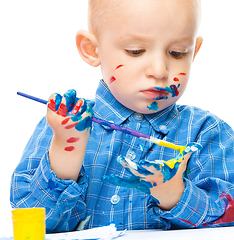 Image showing Little boy is playing with paints