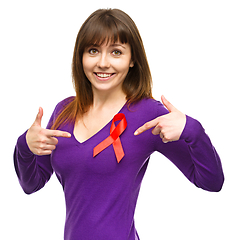 Image showing Woman is pointing to the red awareness ribbon