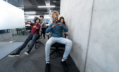 Image showing multiethnics business team racing on office chairs