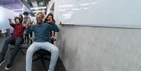 Image showing multiethnics business team racing on office chairs