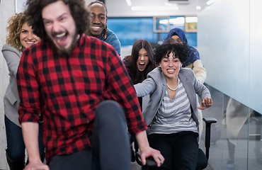 Image showing multiethnics business team racing on office chairs