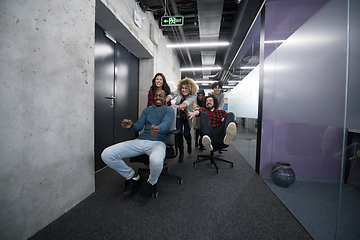 Image showing multiethnics business team racing on office chairs