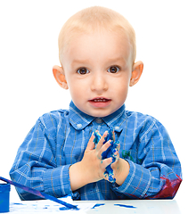 Image showing Little boy is playing with paints