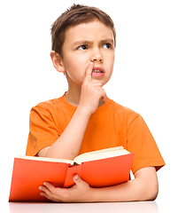 Image showing Young boy is daydreaming while reading book