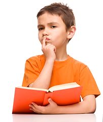 Image showing Young boy is daydreaming while reading book