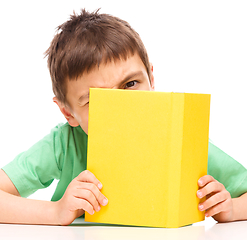Image showing Little boy plays with book