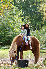 Image showing Two girls with horse