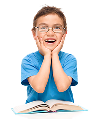 Image showing Astonished little boy is reading a book