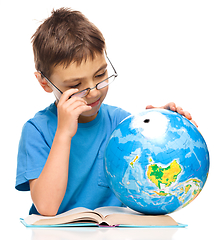 Image showing Little boy is examining globe