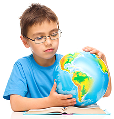 Image showing Little boy is examining globe