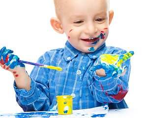 Image showing Little boy is playing with paints