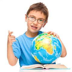 Image showing Little boy is examining globe