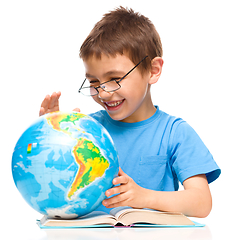 Image showing Little boy is examining globe