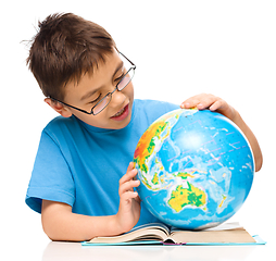 Image showing Little boy is examining globe