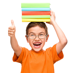 Image showing Little boy is holding a pile of books